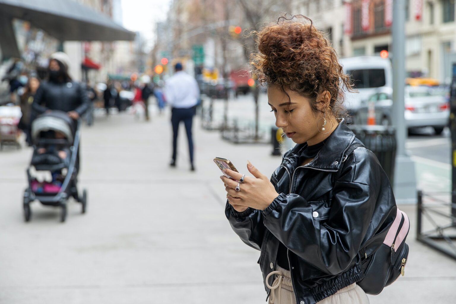 Woman wearing black leather jacket looks at phone.