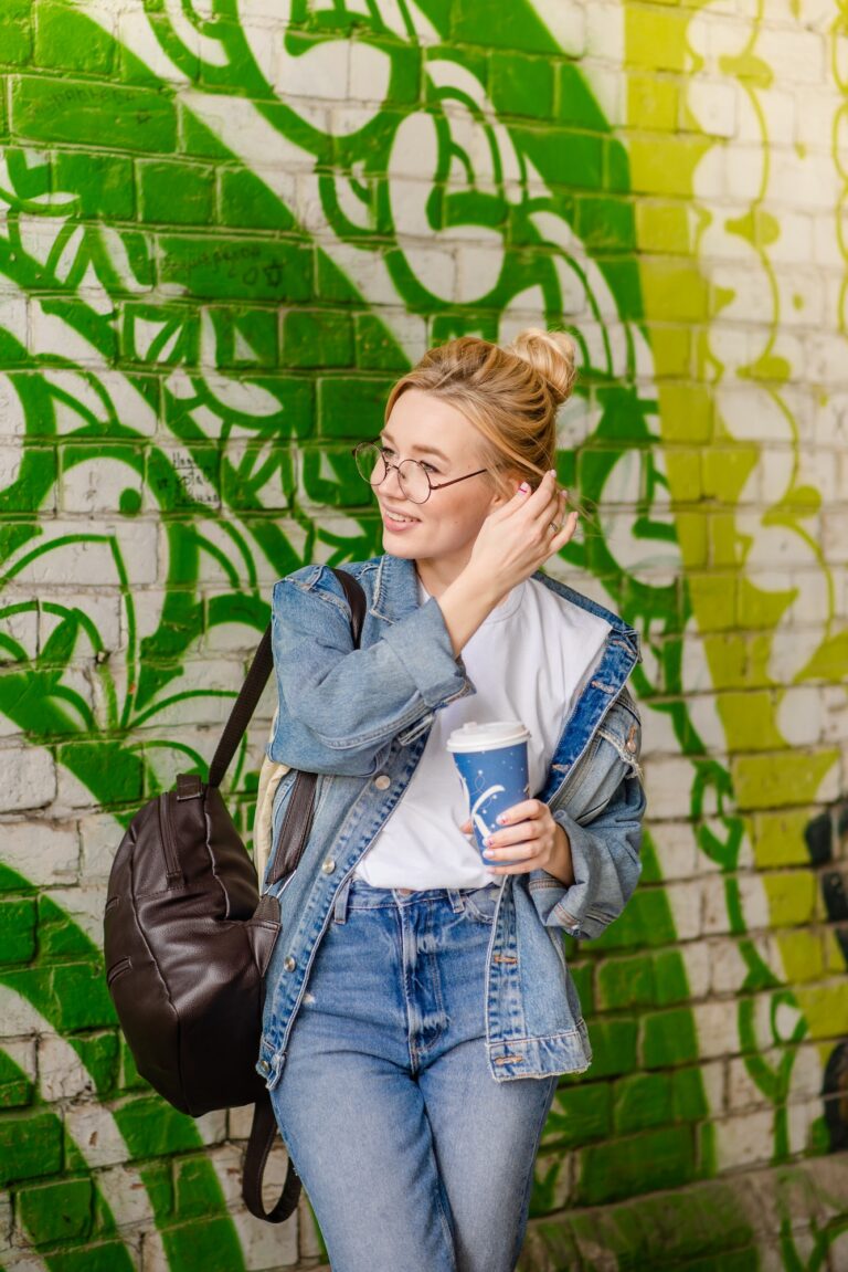 Young beautiful blonde woman on a warm sunny day. Trendy woman wearing glasses and jeans clothes
